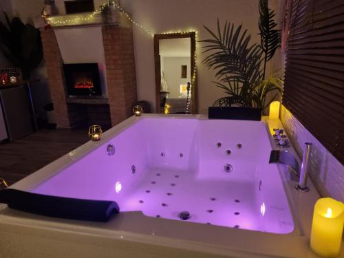 a large bath tub with purple lighting in a room with a fireplace at "Levasion romantique" loft jacuzzi jardin privatif près de Paris in Saint-Prix