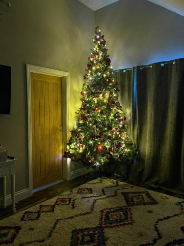 a christmas tree in the corner of a room at Lime Tree Cottage in Tillingham