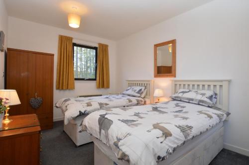 a bedroom with two beds and a mirror at Heronlea Cottage in Dunoon