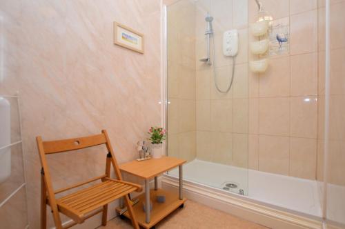 a bathroom with a shower and a table and a chair at Heronlea Cottage in Dunoon