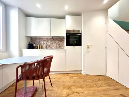 a kitchen with white cabinets and a table and a chair at La Loge Parisienne, 300m gare, Climatisation, Téléphérique in Grenoble