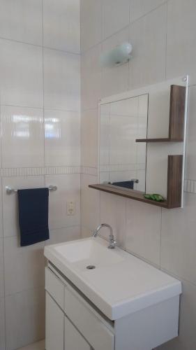 uma casa de banho branca com um lavatório e um espelho em Casa com 6 suítes e piscina, a 160m da praia em Florianópolis