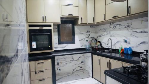 eine Küche mit weißen Marmoroberflächen und einer Mikrowelle in der Unterkunft العيون شارع 24 نوفمبر قرب قروان in El Aaiún