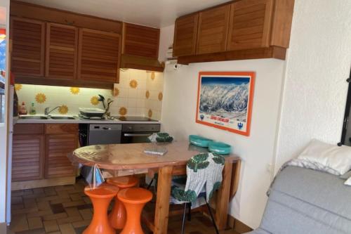 une cuisine avec une table et quelques tabourets orange dans l'établissement Cozy and charming 40 m in Le Monêtier-les-Bains, au Monêtier-les-Bains