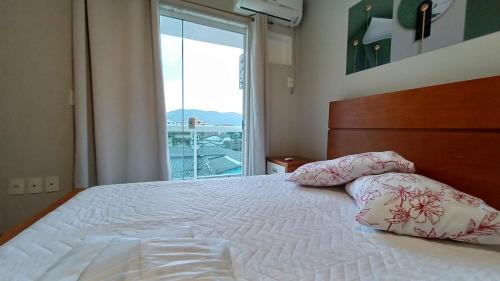 a bedroom with a bed with two pillows and a window at Apart Angra dos Reis I in Angra dos Reis