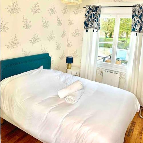 un lit blanc avec une tête de lit bleue et une fenêtre dans l'établissement Maison 3 ch. Garage, jardin, 10 min circuit, au Mans