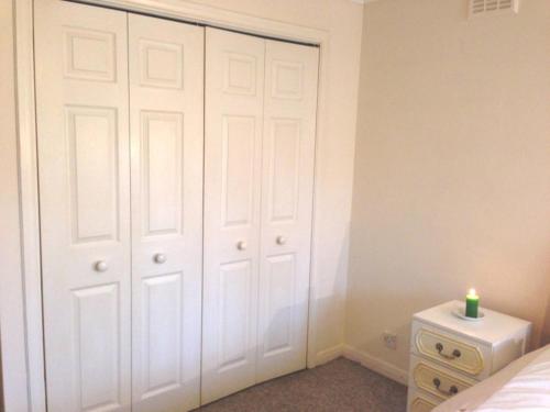 a bedroom with a white closet with a candle on it at Cozy bedroom in well equipped apartment in Leatherhead