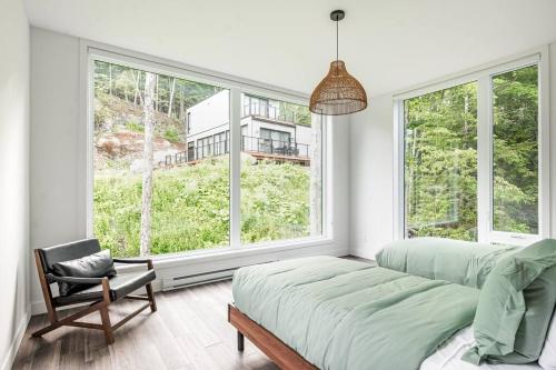 um quarto com uma cama, uma cadeira e janelas em Modern Contemporary Luxury Chalet em La Conception