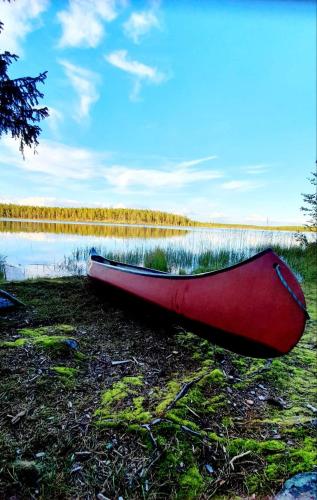 a red canoe sitting on the shore of a lake at Stationshuset Dalarna Apartments in Sörsjön