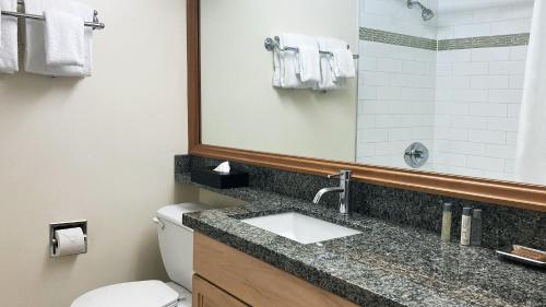 a bathroom with a sink and a toilet and a mirror at Mountain Side Hotel Whistler by Executive in Whistler