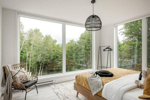 een slaapkamer met een bed en een groot raam bij Modern Luxurious Chalet near Tremblant in La Conception