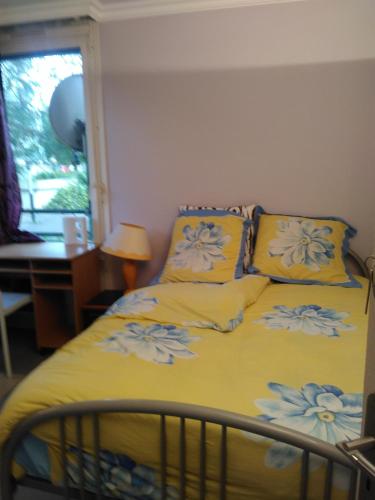 un lit avec des draps jaunes et des fleurs bleues dessus dans l'établissement Ina-Olivia F5 à Massy, à Massy
