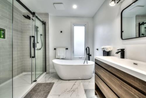 uma casa de banho branca com uma banheira e uma cabina de duche em vidro. em Lux. 4BR House with Pool near DT em Brossard