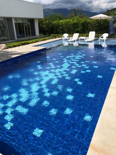 a swimming pool with blue water and white chairs at Casa Tótem inmersión inolvidable en la naturaleza in Apulo