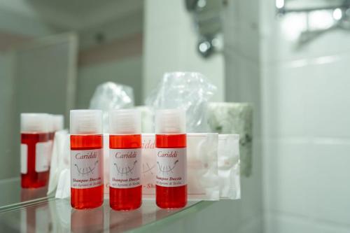 three bottles of red lipstick sitting on a glass shelf at Hotel Corallo in Taormina