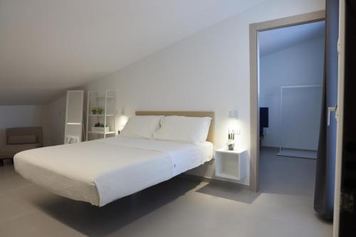 a white bedroom with a large bed and a mirror at Ruffini Rooms in Termoli