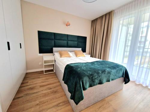 a bedroom with a large bed and a large window at Zakopiańskie Igliwie Apartament & Spa in Zakopane