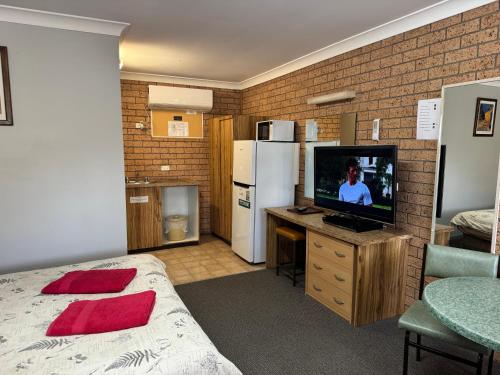 a room with a bed and a television and a kitchen at Three Ways Motel in Gilgandra