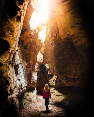 a woman is walking through a cave at Nunyara - Mountain Views, Rural, Kangaroos, Birds in Newnes Junction