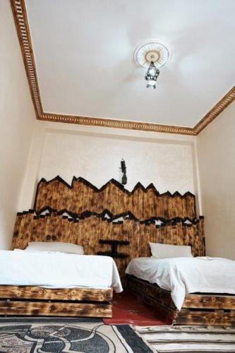 a bedroom with two beds and a ceiling at Dounia Hostel in Tinerhir