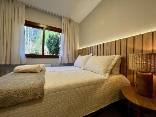 a bedroom with a large bed with a window at Stuttgart 210 - Apê em Gramado em local tranquilo in Gramado