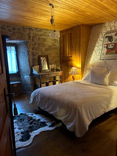 ein Schlafzimmer mit einem großen Bett in einem Steinzimmer in der Unterkunft La Maison de Paul en Aubrac - Lozère in Fontans