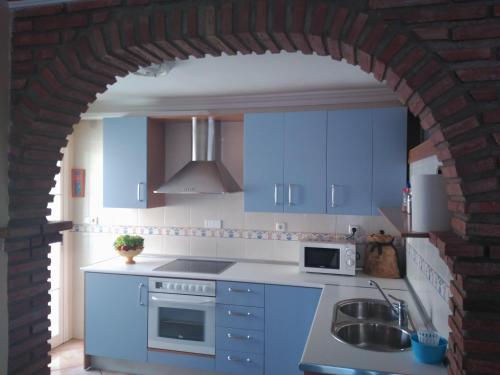 a kitchen with blue cabinets and a brick wall at Apartamento Nandy e Isa in Caleta De Velez