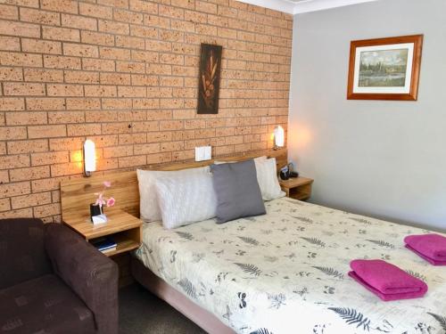 a bedroom with a bed and a brick wall at Three Ways Motel in Gilgandra