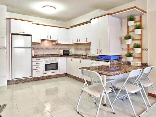 een keuken met witte kasten en een tafel en stoelen bij Apartamento completo con wifi en Betanzos in Betanzos