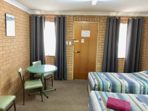 a room with two beds and a table and chairs at Three Ways Motel in Gilgandra