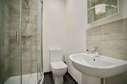 a bathroom with a sink and a toilet and a shower at Apartment by DH ApartHotels in Peterborough
