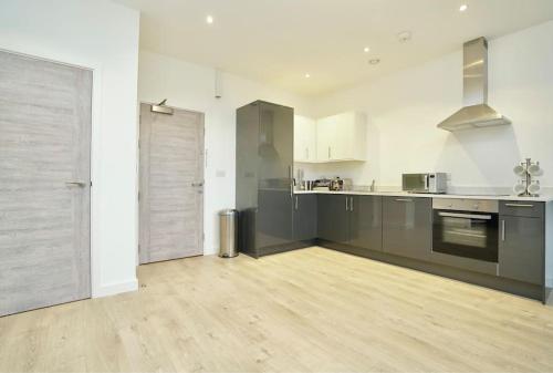 een grote keuken met witte muren en een houten vloer bij Apartment by DH ApartHotels in Peterborough