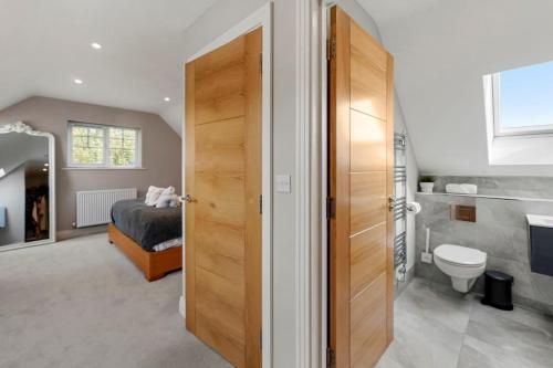 a bedroom with a bed and a bathroom with a toilet at Luxury Detached New 5 Bedroom House Ascot - Parking Private Garden in Winkfield