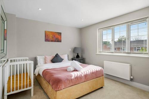 a bedroom with a bed with a crib in it at Luxury Detached New 5 Bedroom House Ascot - Parking Private Garden in Winkfield