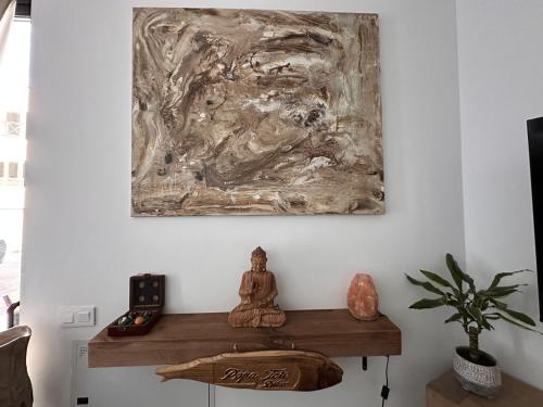 a buddha sitting on a table in a room with a painting at Papá Totë Deluxe in Playa Honda