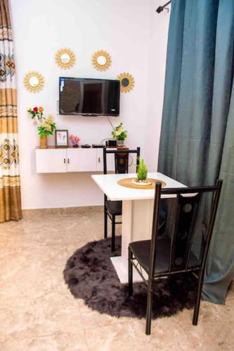 ein Esszimmer mit einem Tisch, Stühlen und einem TV in der Unterkunft Somptueux Studio au cœur de Douala in Douala