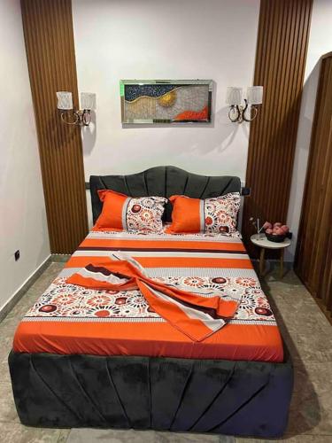 ein Schlafzimmer mit einem Bett mit orangefarbenen Kissen in der Unterkunft Somptueux Studio au cœur de Douala in Douala