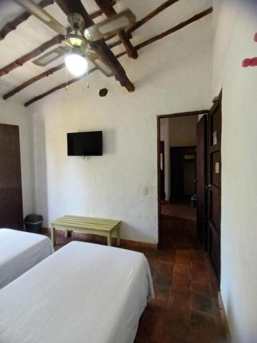 a hotel room with two beds and a television at Casona CHARA in Barichara