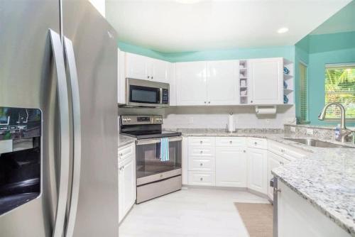 a kitchen with white cabinets and a refrigerator at On The Bay in North Side