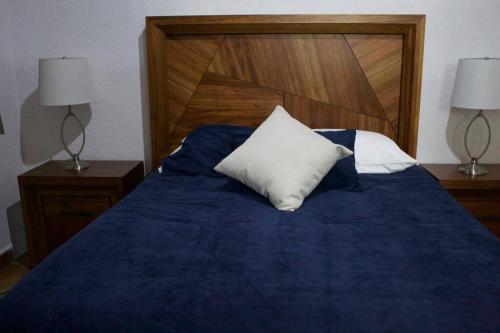 a bed with a blue comforter and a white pillow at NIce & cozy apt in San José Ins. in Mexico City
