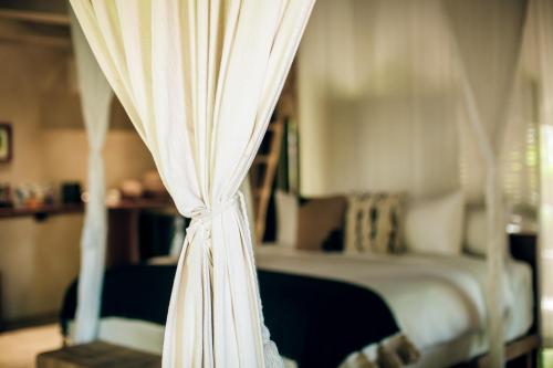 a bed with white curtains in a bedroom at Orchid House Tulum Jungle in Tulum