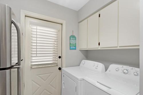 a kitchen with white cabinets and a washer and dryer at Coral Cottage in Saint Simons Island