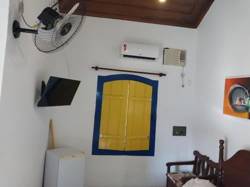 a room with a yellow door and a fan at Pousada Flores da Terra in Paraty