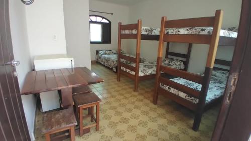 Pokój z łóżkiem piętrowym, stołem i biurkiem w obiekcie Suítes Libertah w mieście Peruíbe