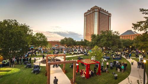 una folla di persone in un parco con un palazzo alto di Hilton Anatole a Dallas