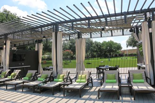 a patio with chairs and tables under a pergola at Hilton Anatole in Dallas