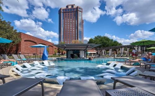 basen z krzesłami i wysoki budynek w obiekcie Hilton Anatole w mieście Dallas