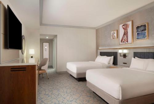 a hotel room with two beds and a flat screen tv at Hilton Anatole in Dallas