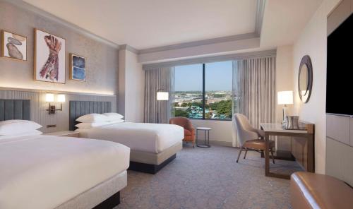 a hotel room with two beds and a desk at Hilton Anatole in Dallas