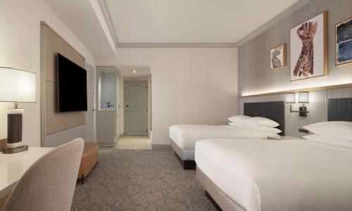 a hotel room with two beds and a television at Hilton Anatole in Dallas